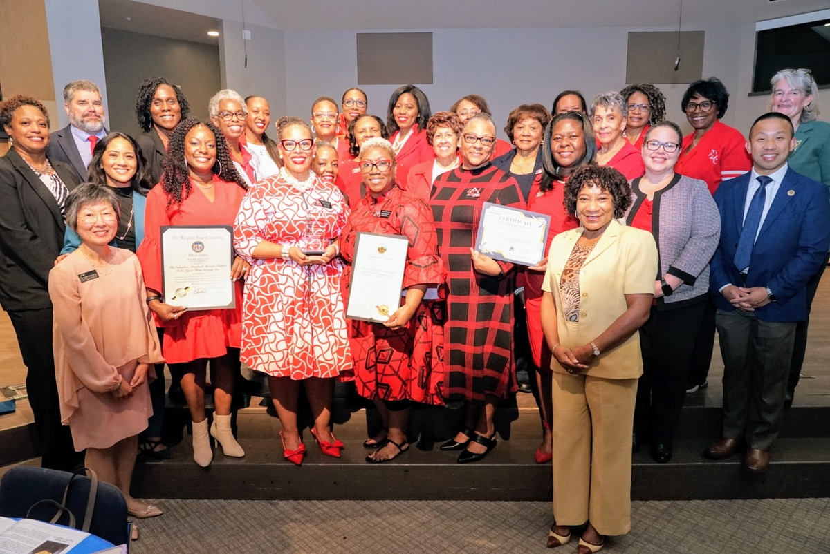 A large group of people wearing black and red stand holding their awards. 