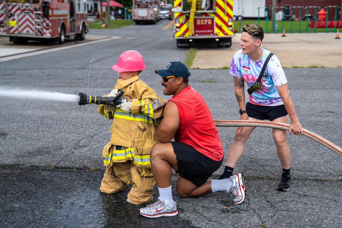 Firefighter with girl shooting water from a hose