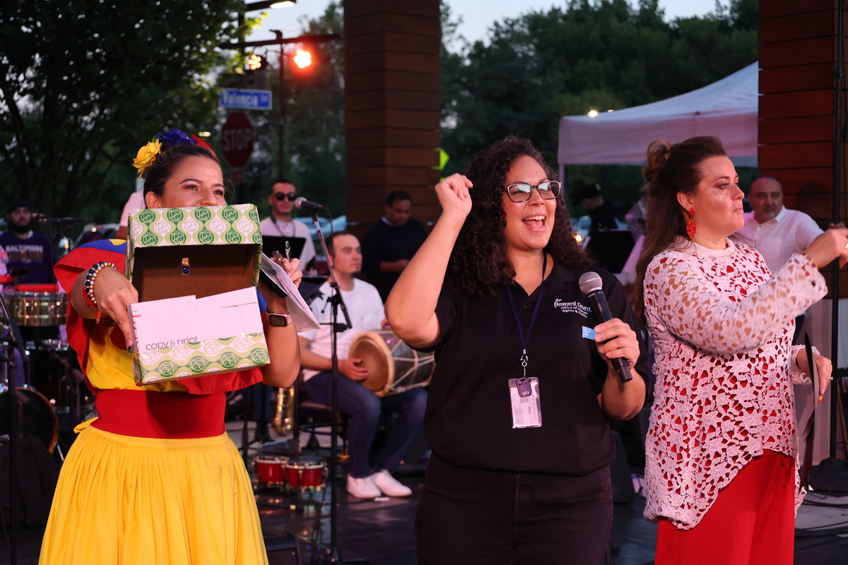 Three women laugh and smile while standing onstage. 