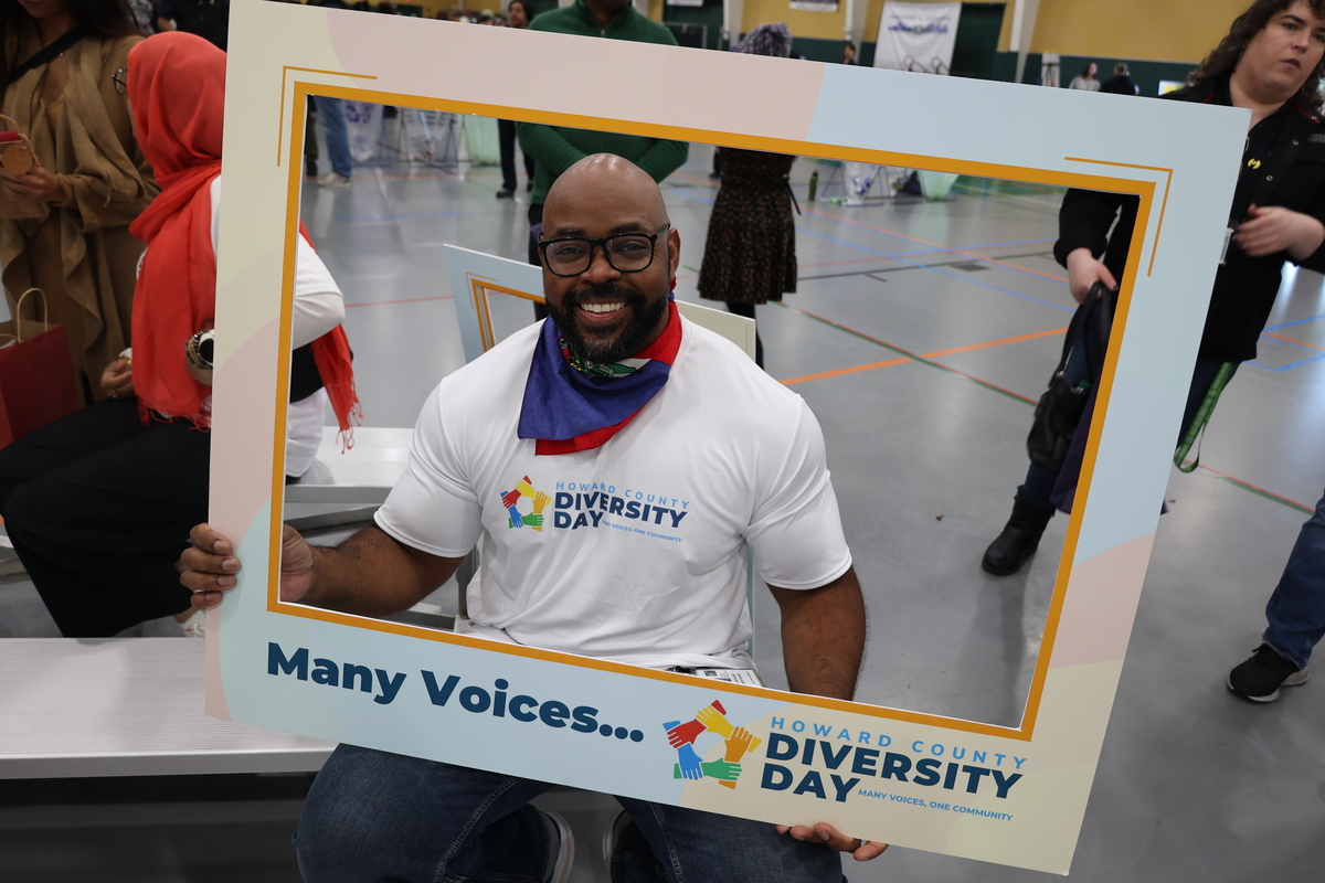 A man smiles while holding a large photo frame