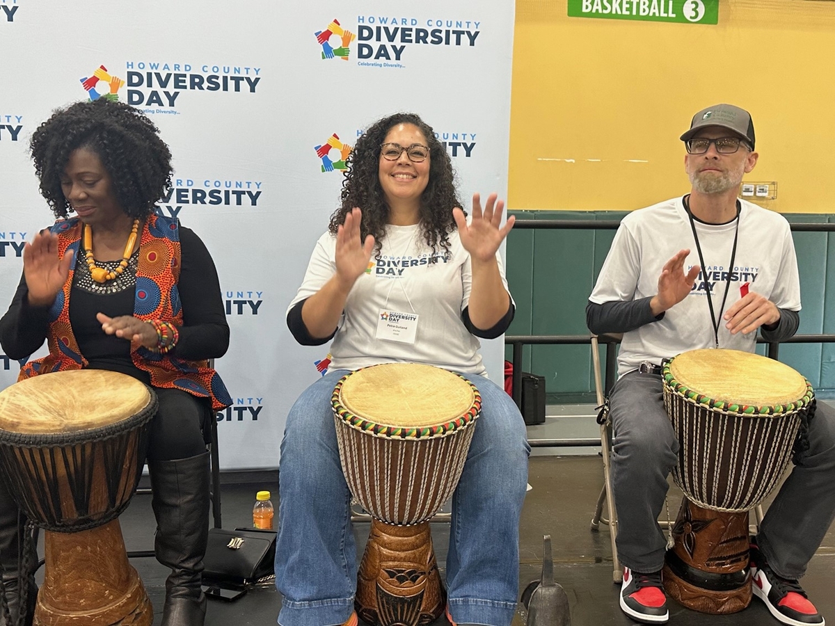 Three people play drums. 