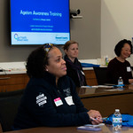 Attendee wearing a navy zip up listens to a presentation.