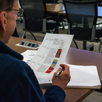 Older man holding paper with book recommendations.