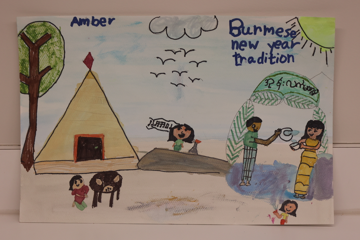 Child's drawing of a family celebrating Burmese New Year on the beach in traditional attire.
