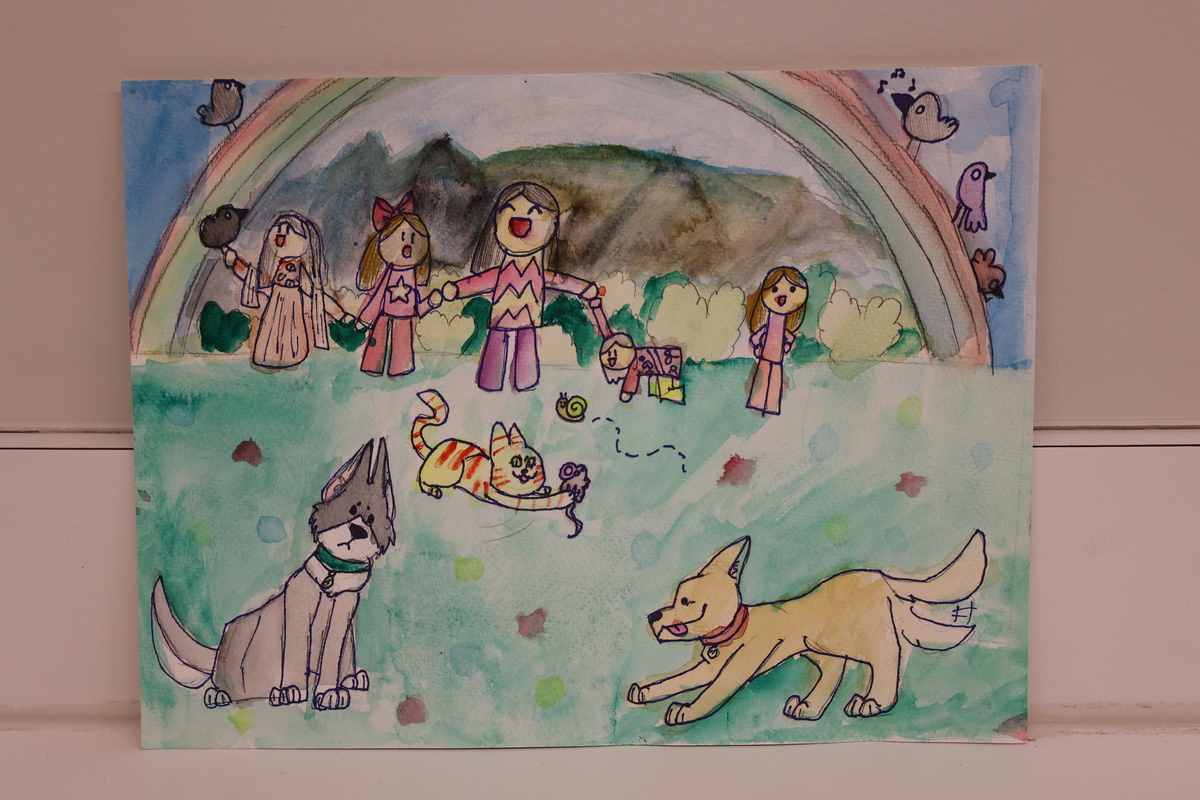 Child's drawing of children playing in a park under a rainbow.