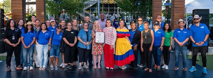An image of the La Alianza Latina Commission, consisting of 23 individuals and the County Executive Calvin Ball on a stage at the Hispanic Heritage Festival.