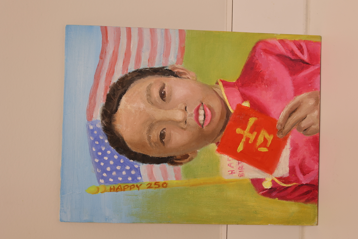 This artwork shows a child holding a Chinese red envelope and the American flag flying in the back.