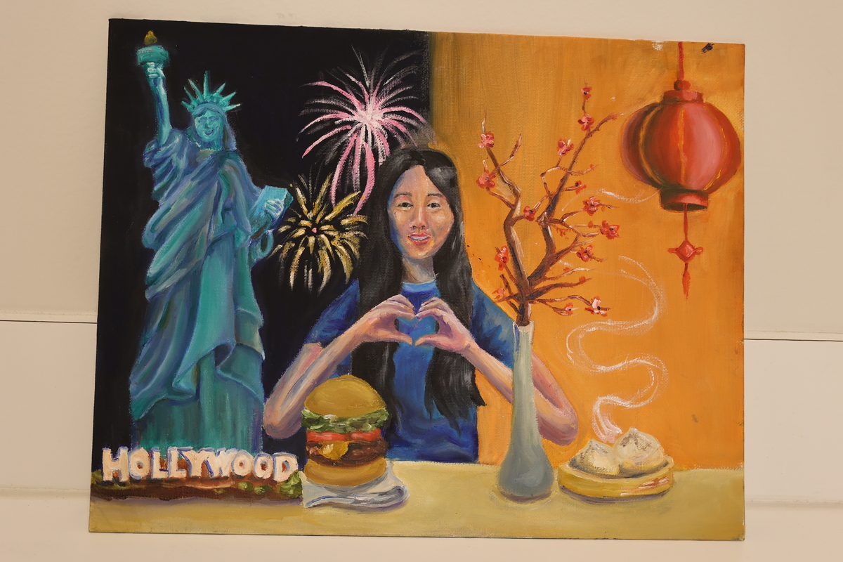 This artwork shows a girl with two sides. One side she has a Chinese lantern and a cherry blossom. The other is the Statue of Liberty with fireworks, while she eats a burger.