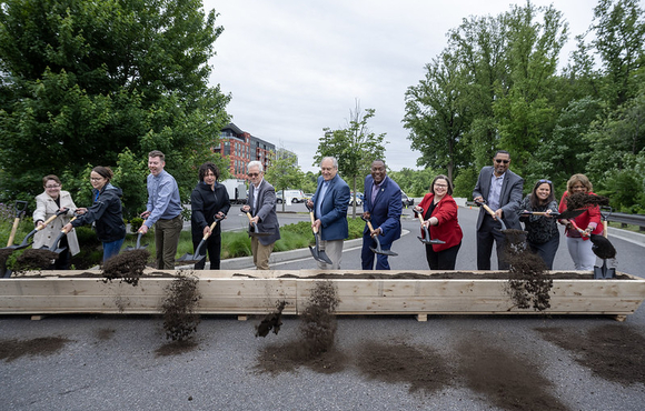 Calvin Ball and a group of people are holding a shovel with dirt in it