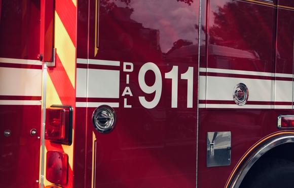 red emergency responder vehicle with white stripes and white font displaying "Dial 911"