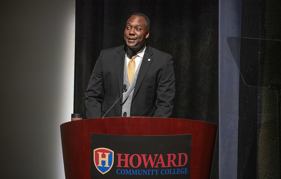 County Executive Calvin Ball standing at a podium on stage at Howard Community College's Smith Theatre delivering his State of the County address.