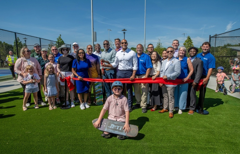  County Executive Calvin Ball posed with fellow elected officials, Department of Recreation & Parks staff members, and community members about to the cut the red ribbon to mark the opening of the amenities at Blandair Regional Park's west area.