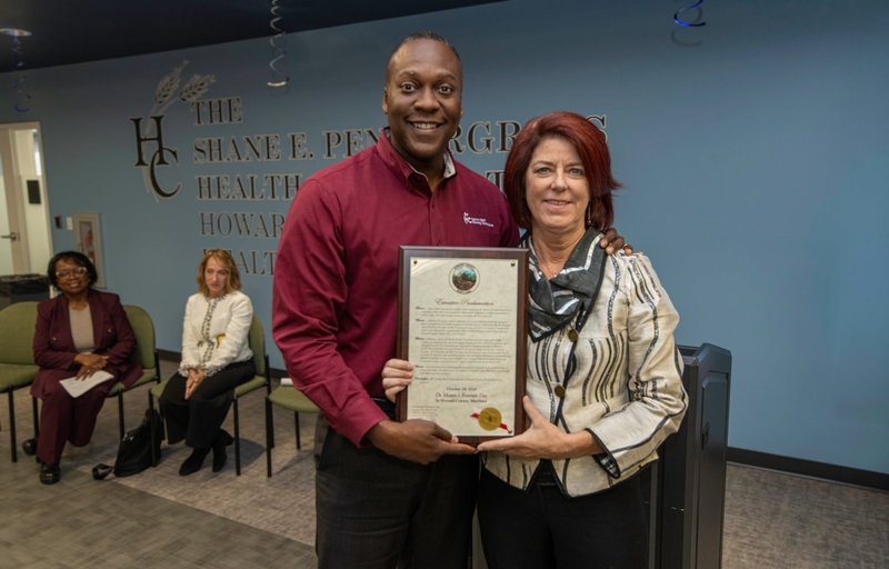 County Executive Calvin Ball posed for a photo with Dr. Maura Rossman together holding up her Executive Proclamation proclaiming October 19, 2026 Dr. Maura Rossman Day in Howard County, Maryland in celebration of her retirement. 