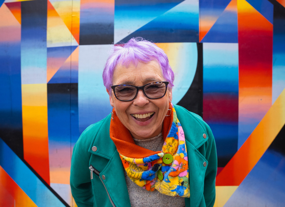 Older adult in front of art work 