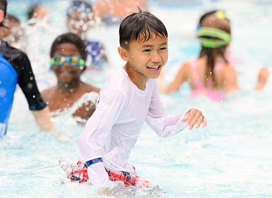 Smiling boy playing in pool with water splashing around