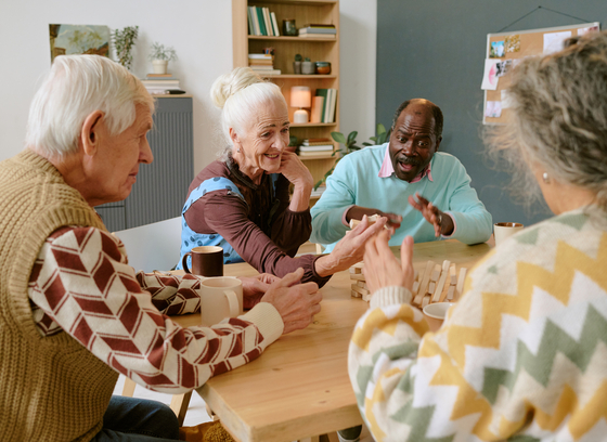 Group of 4 older adults at a table playing jenga.