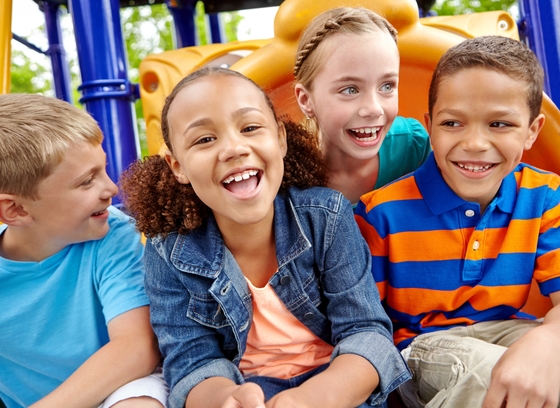 A group of happy, diverse children playing on a playset