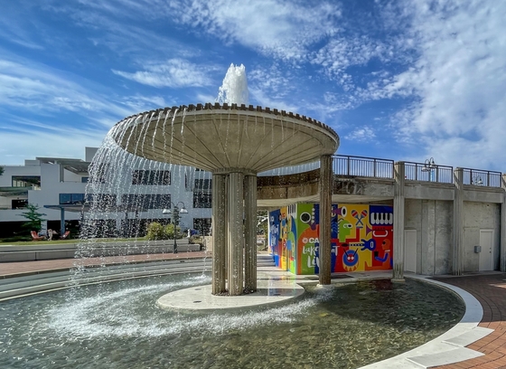 Sunny photograph of the Lake Front Fountain featuring colorful mural art in red, green, yellow, and purple.