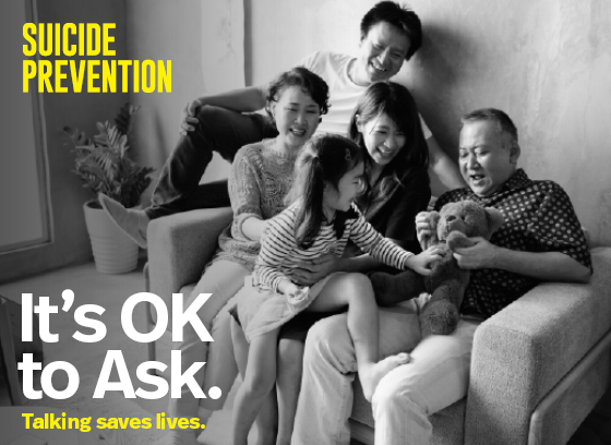 Multigenerational family sitting on a couch and smiling. Black and white photo. Text: Suicide prevention. It's ok to ask. Talking saves lives