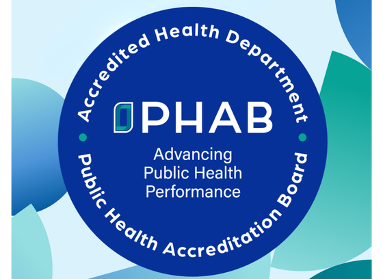 PHAB accreditation badge. "Accredited Health Department. Public Health Accreditation Board." Dark blue circle on background with various light blue and green circles.