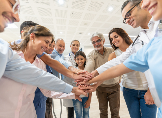 A group of diverse people in a circle making a stack of hands