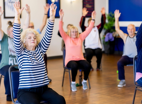 Group of older adults doing chair exercises.