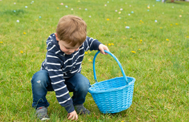 Image of a small boy picking up an easter egg in grass