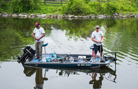 two men standing in a boat fishing