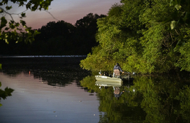 man fishing in a boat at night