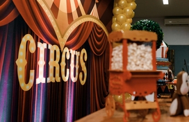 Maroon curtain with sign that says circus and a mini popcorn cart.