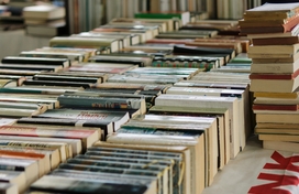 Many books lined up in a row on a table.