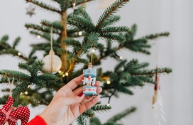 Arm reach out and touching ornament on a Christmas tree.