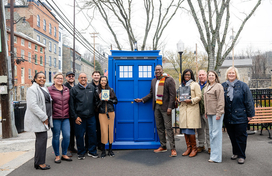 A photo of County Executive Calvin Ball and County staff and local Old Ellicott City community members standing in front of the County's new mobile Little Free Library the #HoCoTARDIS.