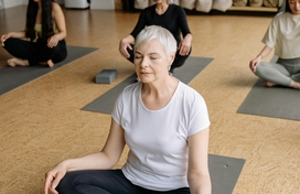 Older woman with white hair and glasses looking at a photo album on a couch with a younger woman with blonde hair.
