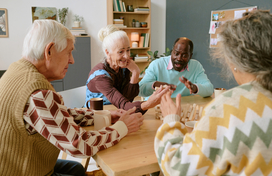 Group of 4 older adults at a table playing jenga.