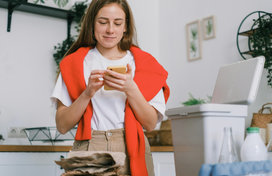 woman checking phone next to recyclable items