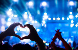 Concert background with someone making heart shape with their hands.
