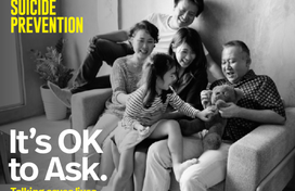 Multigenerational family sitting on a couch and smiling. Black and white photo. Text: Suicide prevention. It's ok to ask. Talking saves lives