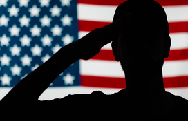 Silhouette of soldier saluting in front of American flag