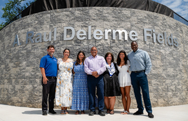 County Executive Calvin Ball posed for a photo with Raul Delerme and his family and Department of Recreation & Parks Director Nick Mooneyhan in front of the stone retaining wall at the baseball diamonds at Centennial Park West.