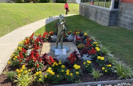 Linwood Center Garden. Statue of a child in a bed of red and yellow flowers