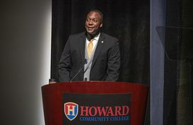 County Executive Calvin Ball standing at a podium on stage at Howard Community College's Smith Theatre delivering his State of the County address.