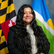 Monica Perez Mills pictured in front of Maryland State and Howard County Flags. 