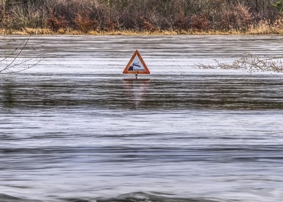 A flooded road with a submerged road sign.
