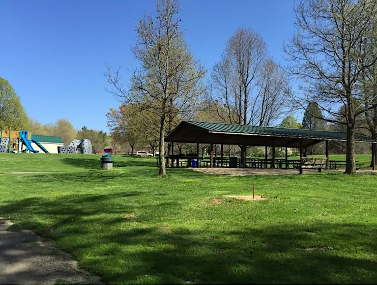 Wide shot of park with a picnic pavilion, blue sky, and green grass
