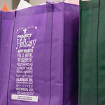 Purple, non-woven tote bag with the logo of Project Holiday in white.