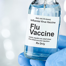 Gloved hand holding vial of flu vaccine
