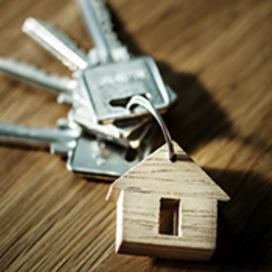 A keyring with four silver keys and a wooden charm in the shape of a house