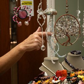Handcrafted beaded art hanging with a person touching one of the items