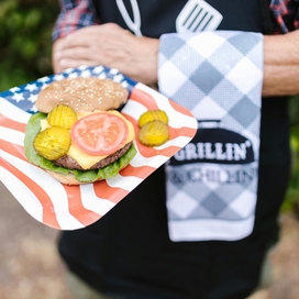 Person holding a plate with a open faced hamburger on it